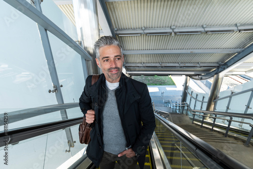 Stylish commuter ascending escalator in modern transport station photo