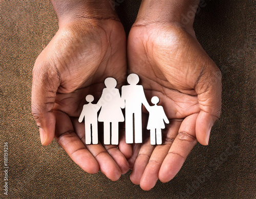 Man holding paper family figures on light blue background, top view. Insurance concept