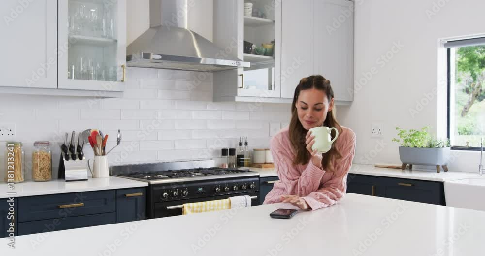 Smiling woman in kitchen enjoying coffee while checking smartphone messages, copy space Smiling woman in kitchen enjoying coffee while checking smartphone messages, copy space