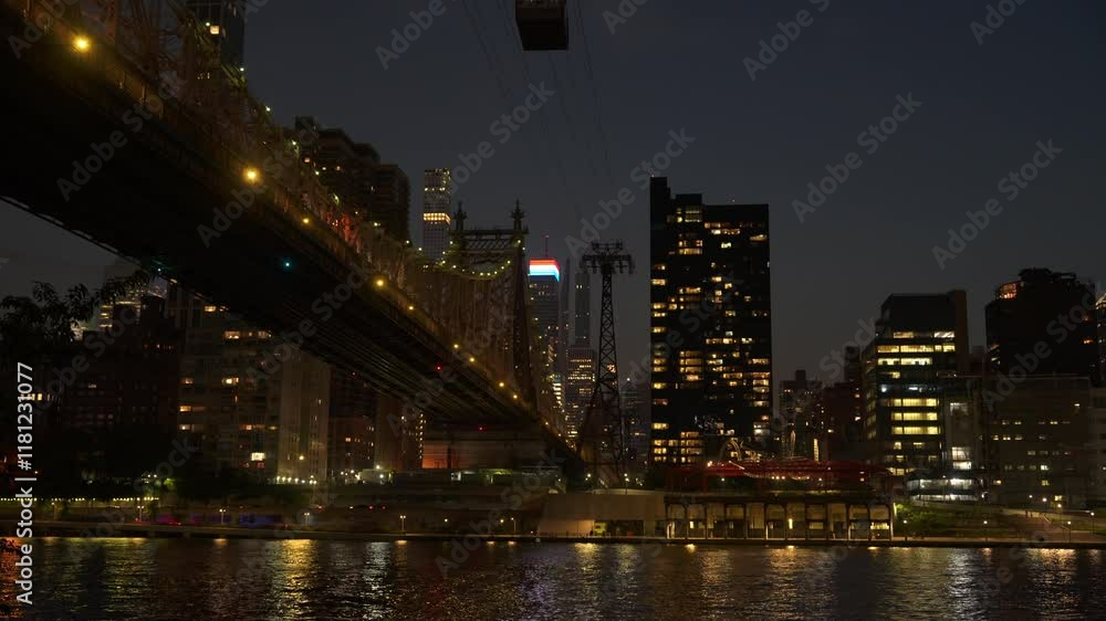 The Queensboro Bridge glows with golden lights, stretching across the calm river beneath the night sky. The surrounding city skyline, with illuminated buildings, creates a stunning urban landscape. The Queensboro Bridge glows with golden lights, stretching across the calm river beneath the night sky. The surrounding city skyline, with illuminated buildings, creates a stunning urban landscape.
