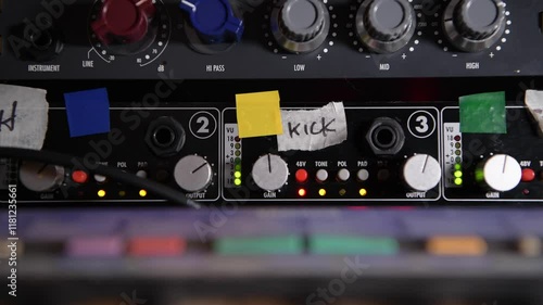 Adjusting the gain knobs on a vintage analog microphone preamp during a recording session