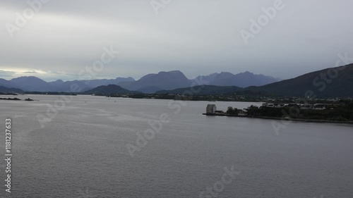 Calm waters reflecting cloudy sky with Alesund, Norway city skyline and Sunnmore Alps mountain range in the background, creating a peaceful and scenic view, panning shot photo