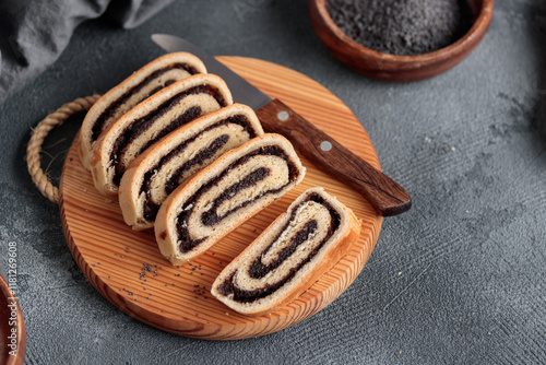 Bejgli, home-baked poppy seed roll, traditional Hungarian, Eastern European Christmas and Easter sweet bread in slices on a wooden cut board, with copy space photo