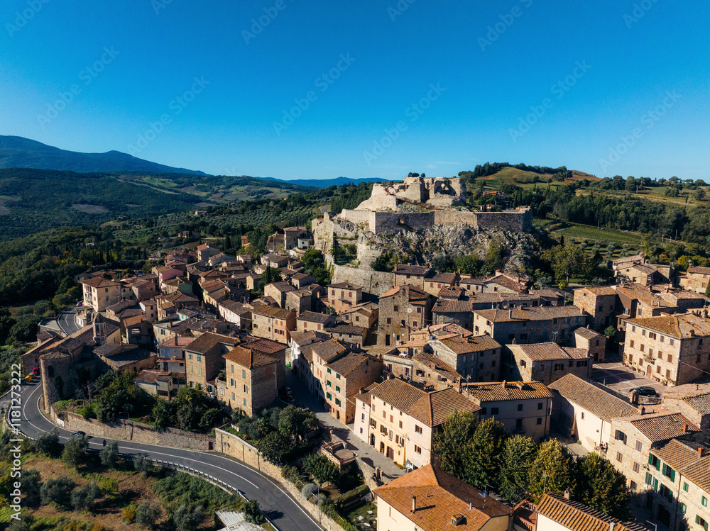 Aerial view of charming medieval town with picturesque rooftops and ancient fortress surrounded by scenic countryside and mountains, Castiglione d'Orcia, Italy. Aerial view of charming medieval town with picturesque rooftops and ancient fortress surrounded by scenic countryside and mountains, Castiglione d'Orcia, Italy.