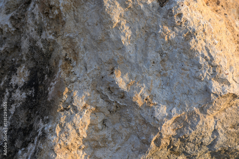 Textured surface of weathered rock reflecting warm sunlight at sunset in a serene landscape Textured surface of weathered rock reflecting warm sunlight at sunset in a serene landscape