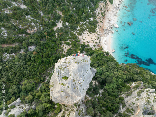 Aerial view of guglia di goloritze rock formation with climbers and turquoise water, Baunei, Italy. photo