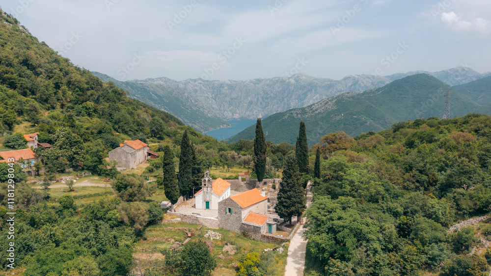 Aerial view of a picturesque village with a historic church surrounded by serene mountains and lush greenery, Herceg Novi, Montenegro. Aerial view of a picturesque village with a historic church surrounded by serene mountains and lush greenery, Herceg Novi, Montenegro.