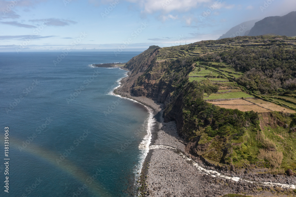 Aerial view of breathtaking coastline with cliffs and a vibrant rainbow over the ocean, Fajazinha, Azores, Portugal. Aerial view of breathtaking coastline with cliffs and a vibrant rainbow over the ocean, Fajazinha, Azores, Portugal.