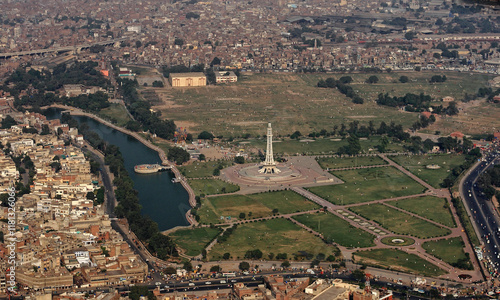 Aerial view of the bustling cityscape featuring the iconic Minar e Pakistan and lush greenery of the park along the river, Lahore, Pakistan.