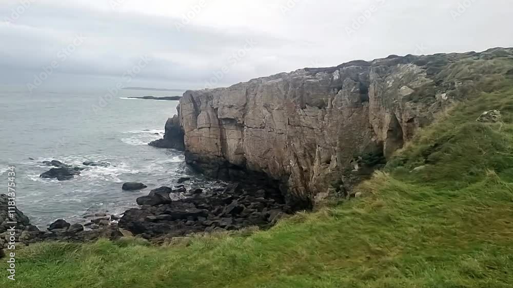 Rugged fractured Welsh Anglesey coastline overlooking cold windy seascape waves and tide pan left