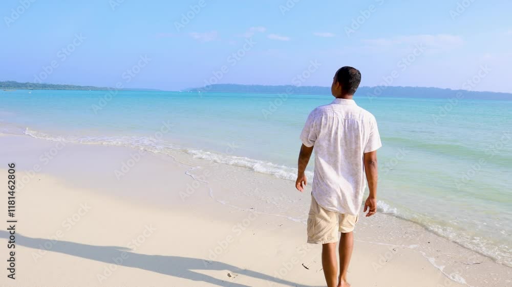 isolated man walking at pristine white sand beach with rolling sea waves at morning from flat angle video is taken at Radhanagar Beach at Havelock Island in the Andaman and Nicobar Islands. isolated man walking at pristine white sand beach with rolling sea waves at morning from flat angle video is taken at Radhanagar Beach at Havelock Island in the Andaman and Nicobar Islands.