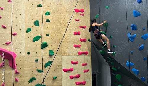 Girl climbing on practical wall indoor, bouldering training photo