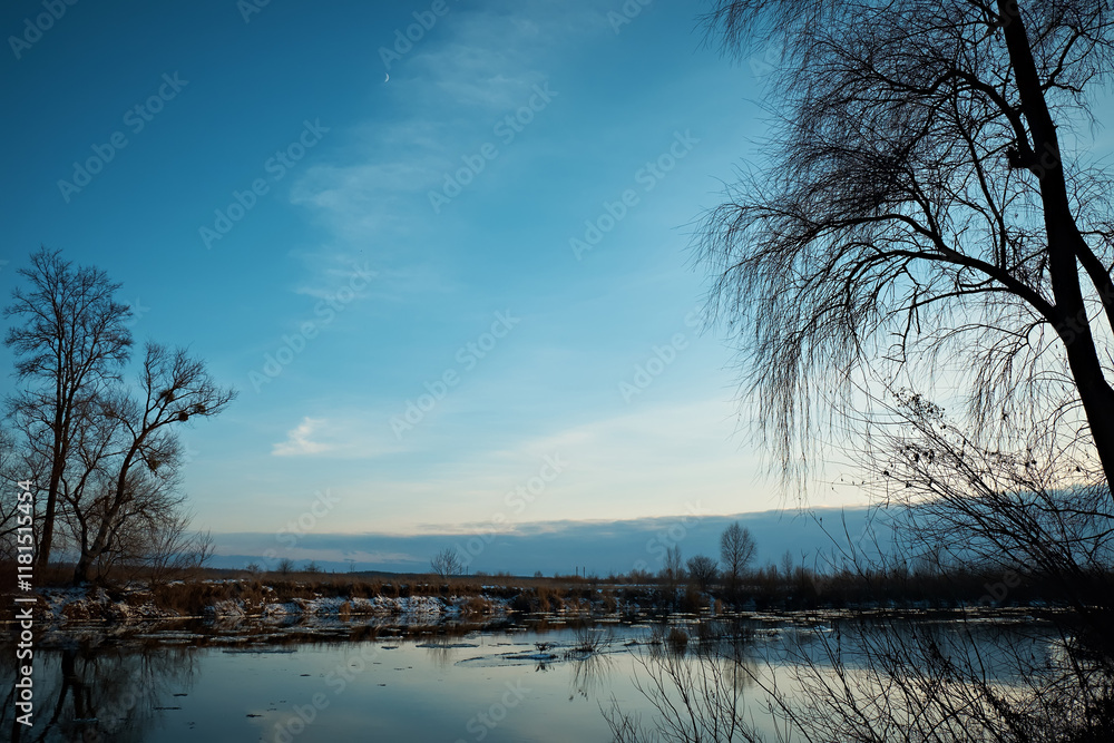 Early spring river landscape, bare trees without leaves against a blue sky. Shot on a cool spring day. Early spring river landscape, bare trees without leaves against a blue sky. Shot on a cool spring day.