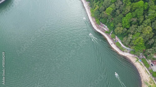 A speedboat glides smoothly across the shimmering waters of Telaga Sarangan, Magetan, framed by lush mountains and creating a stunning contrast between nature and adventure. photo