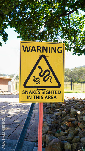 Warning sign alerts visitors to recent snake sightings in a public outdoor area near a park photo