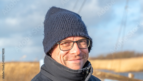 Junger Mann mit Brille und Mütze grinsend falten photo