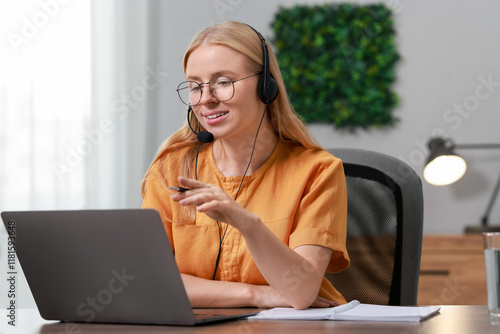 Obraz na plátně Interpreter in headset having video chat via laptop at table indoors