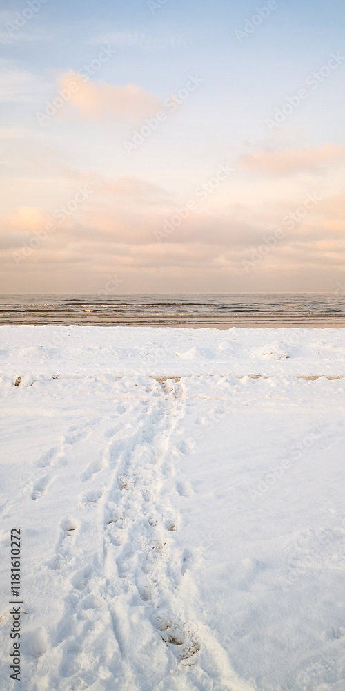 Tranquil winter beach with snowy shoreline and serene ocean waves at sunrise Tranquil winter beach with snowy shoreline and serene ocean waves at sunrise
