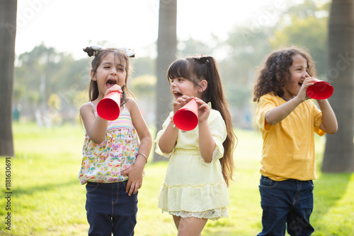 Naughty Kids Playing With Paper Megaphone Loudspeaker In Park