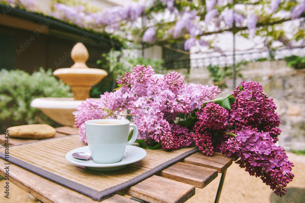 Romantic image of spring lilac bouquet with cup of coffee on the table in outdoor cafe Romantic image of spring lilac bouquet with cup of coffee on the table in outdoor cafe