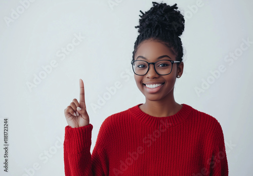 Portrait of a happy young woman wearing glasses, smiling and pointing her finger upward, isolated on a white background. 