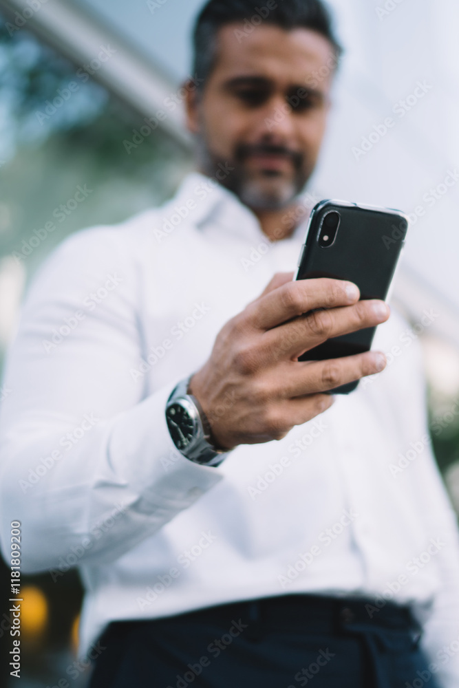 Below view of blurred businessman connecting to wireless for browsing banking application on modern smartphone device, male downloading files and texting via selective mobile gadget with 4g internet Below view of blurred businessman connecting to wireless for browsing banking application on modern smartphone device, male downloading files and texting via selective mobile gadget with 4g internet