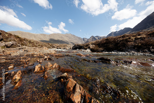 Scenic river wending through rugged landscapes of Isle of Skye, Scotland on a bright day photo