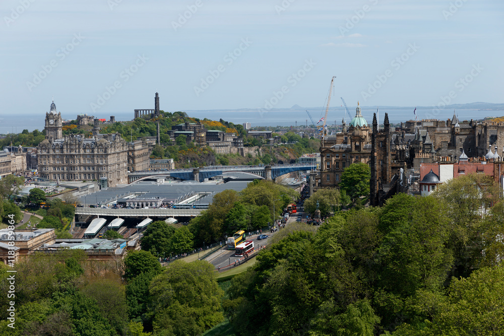 Expansive view of Edinburgh showcasing historic architecture, modern infrastructure, and lush greenery on a sunny day