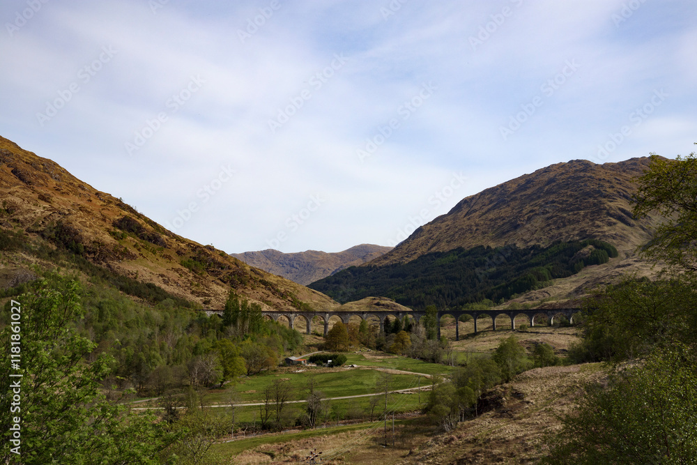 Naklejka premium Scenic view of the iconic bridge spanning a lush valley in the Scottish highlands under a clear sky