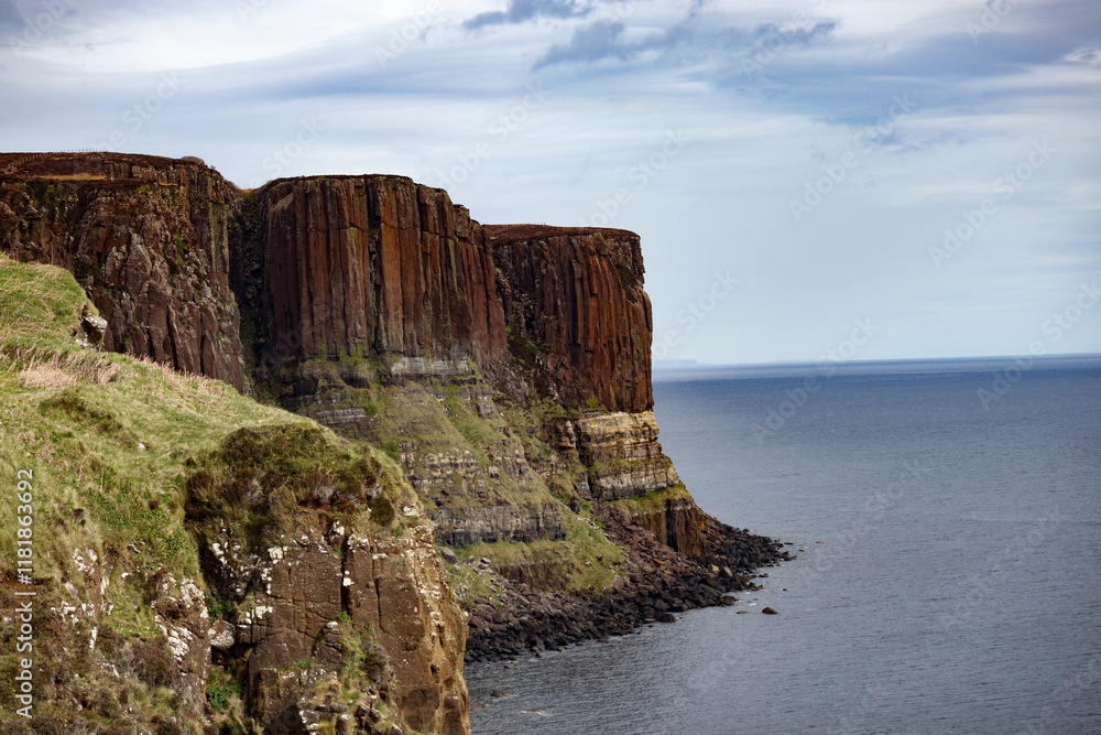 Dramatic cliffs rise above the calm waters of the Isle of Skye in Scotland on a clear day Dramatic cliffs rise above the calm waters of the Isle of Skye in Scotland on a clear day