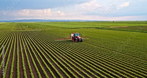 Farmer in tractor spraying an industrial soybean crops