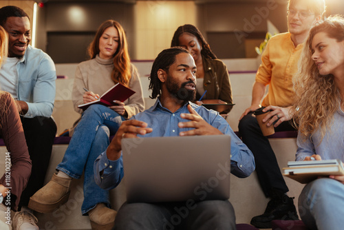 Professor leading discussion with university students using laptop