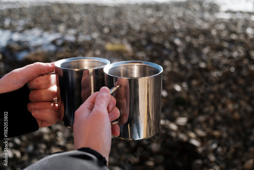 Thermos. Thermocup. Metal cup. Travel. Camping. Hiking. Boy and girl drinking tea. Family travel. Close-up. Steam from tea. Coffee. Coffee to go. Winter travel photo