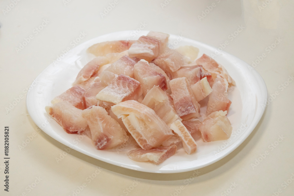 Pangasius fish fillet by pieces on the white plate. Fresh fish fillet. Pangasius fish fillet by pieces on the white plate. Fresh fish fillet.