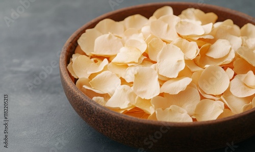 An intimate close-up of soft white rose petals, blending in a brown wooden bowl.