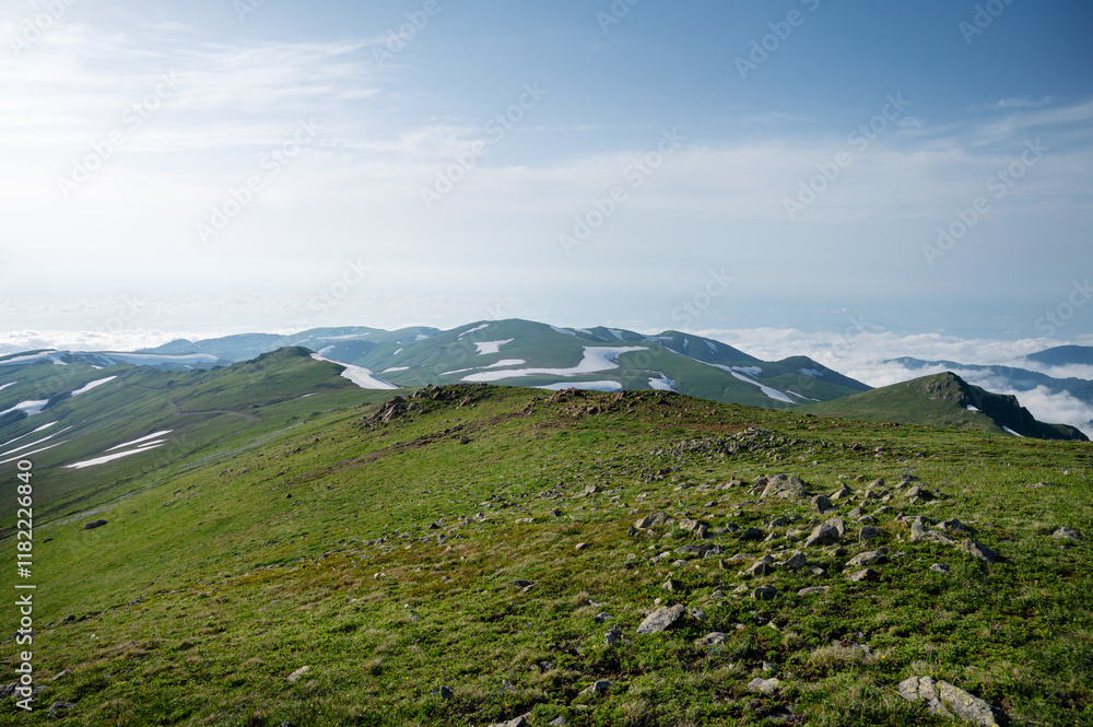 Green mountains with melting snow and fresh grass under cloudy sky. Green mountains with melting snow and fresh grass under cloudy sky.