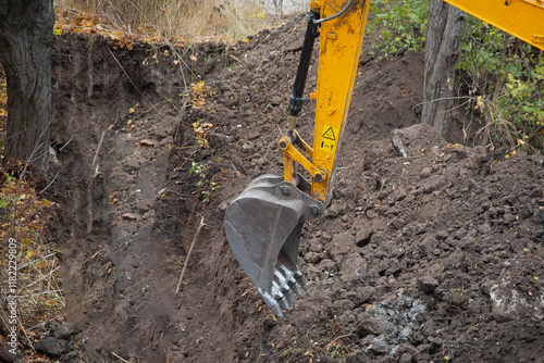 Close-up of an excavator bucket over a dug trench, a pit for the foundation excavated by the excavator, the work of the excavator bucket. photo