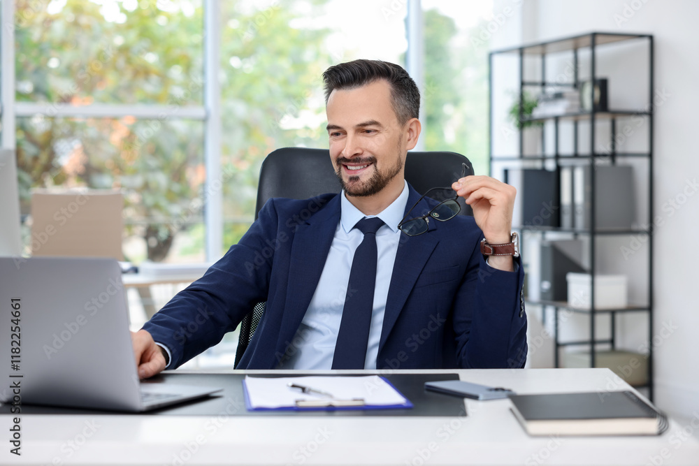 Happy banker working with laptop at table in office Happy banker working with laptop at table in office