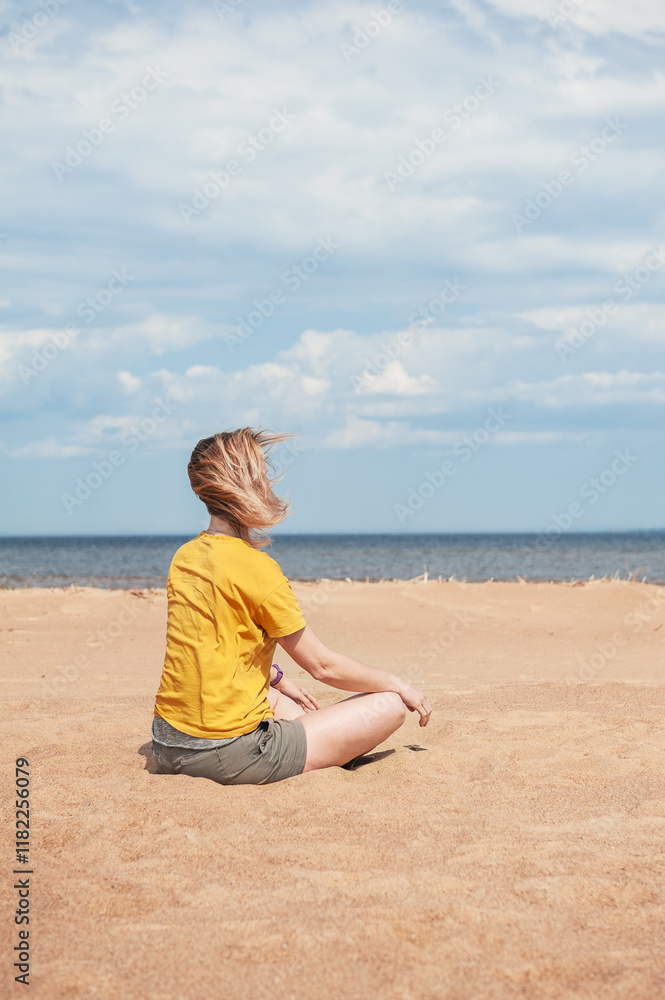 Beautiful woman sits alone on a sandy beach under a serene sky Beautiful woman sits alone on a sandy beach under a serene sky