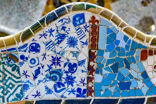Close-up of blue and brown mosaic pieces, fence of serpentine bank in main square below hypostyle of Parc Guell by Antoni Gaudi, surreal style design, sunny day in Barcelona, ​​Catalonia, Spain