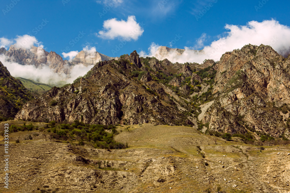 Fototapeta premium Caucasus, mountainous rocky view, blue sky with white cottony clouds