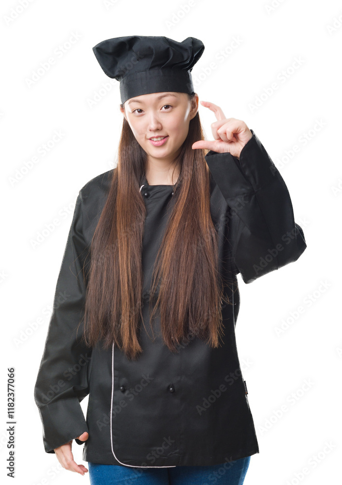 Young Chinese woman over isolated background wearing chef uniform smiling and confident gesturing with hand doing size sign with fingers while looking and the camera. Measure concept. Young Chinese woman over isolated background wearing chef uniform smiling and confident gesturing with hand doing size sign with fingers while looking and the camera. Measure concept.