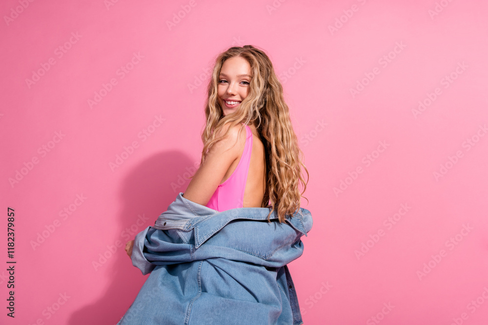 Fototapeta premium Joyful young woman with a denim jacket against a vibrant pink backdrop exuding a charming casual vibe