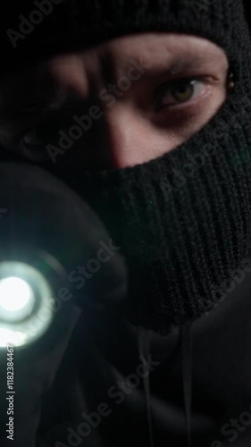 Masked Man Holding Flashlight in Darkness
