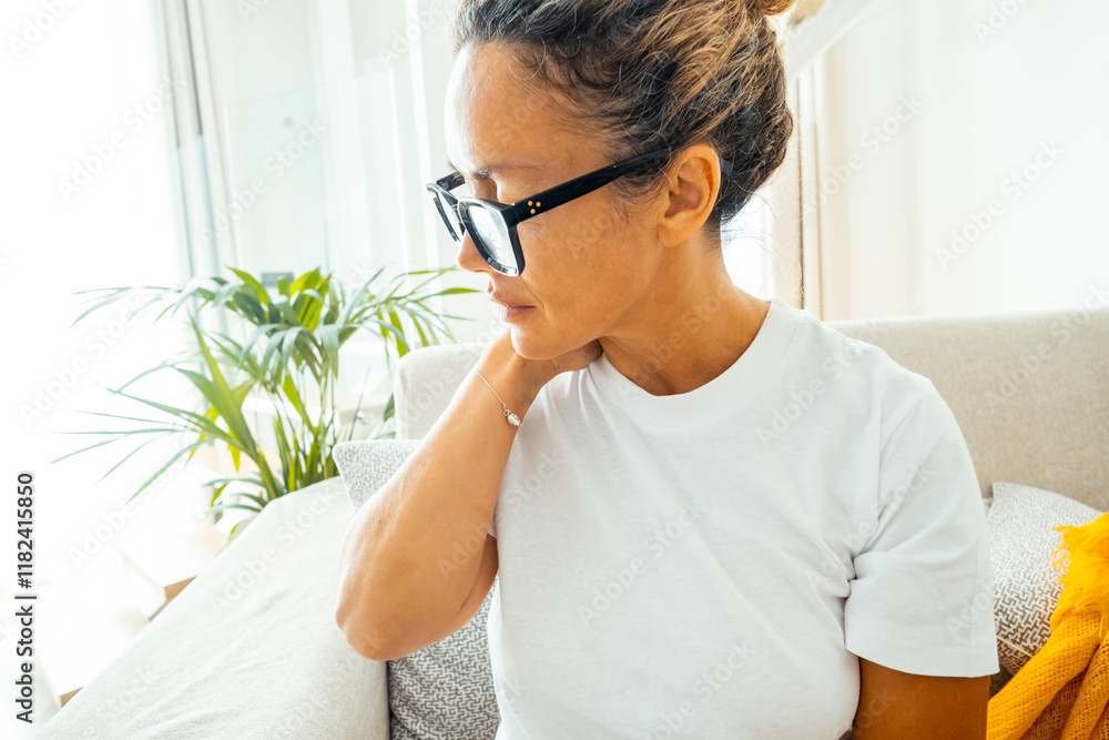 Middle-aged woman massaging her aching neck with visible discomfort, possibly due to bad posture, chronic tension, or health issues like arthritis, showing the impact of sedentary lifestyles Middle-aged woman massaging her aching neck with visible discomfort, possibly due to bad posture, chronic tension, or health issues like arthritis, showing the impact of sedentary lifestyles
