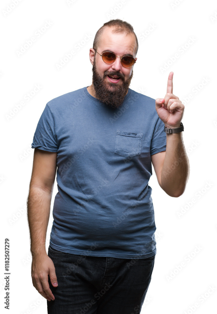 Fototapeta premium Young caucasian hipster man wearing sunglasses over isolated background pointing finger up with successful idea. Exited and happy. Number one.