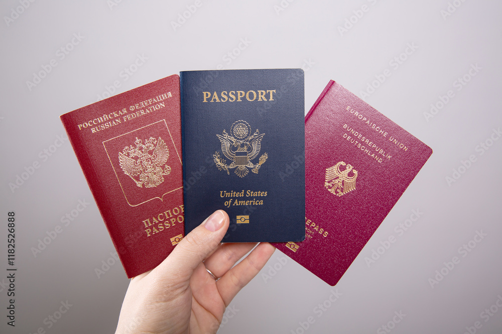 A female hand holding an American passport and a Russian and a German passport A female hand holding an American passport and a Russian and a German passport