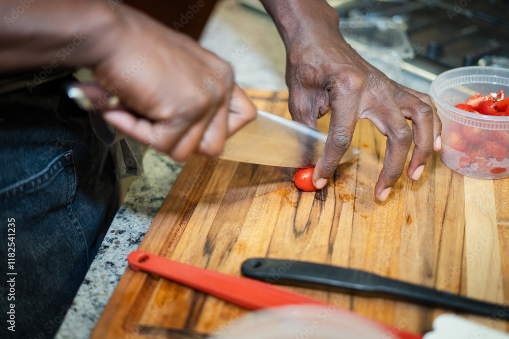 Obraz premium Chef Hands Cutting A Cherry Tomato On A Wooden Cutting Board