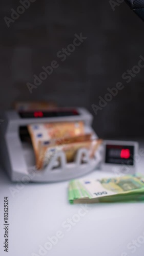 Wallpaper Mural Person places orange bills into cash counting device. Male hand takes counted euro and places on the desk near one hundred stack. Close up. Blurred image. Vertical video. Torontodigital.ca