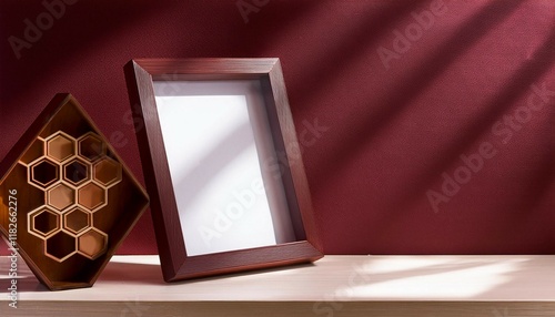 a wooden frame mockup on a beige bookshelf tilted viewed from side angle window reflection in frame mockup blank white mockup maroon wall with honeycomb patterns a small maroon sculpture photo